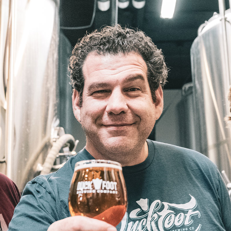 Brett Goldstock co-founder of Duck Foot holding a glass of beer